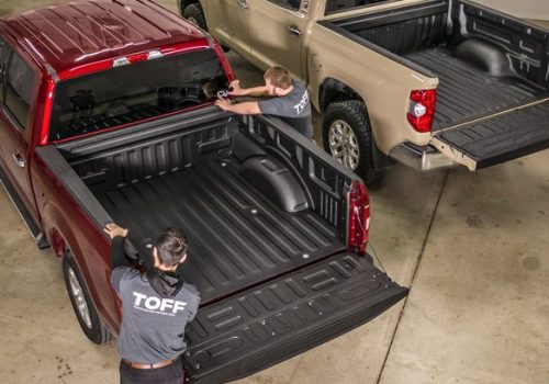 TOFF employees diligently detailing a red truck in preparation for showroom display, showcasing TOFF's commitment to excellence in the bedliner dealership arena.